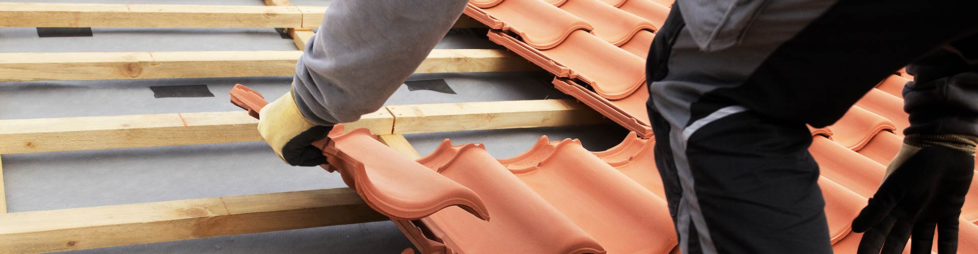 Dachdecker verlegt Dachziegel auf einer neuen Dachlattung